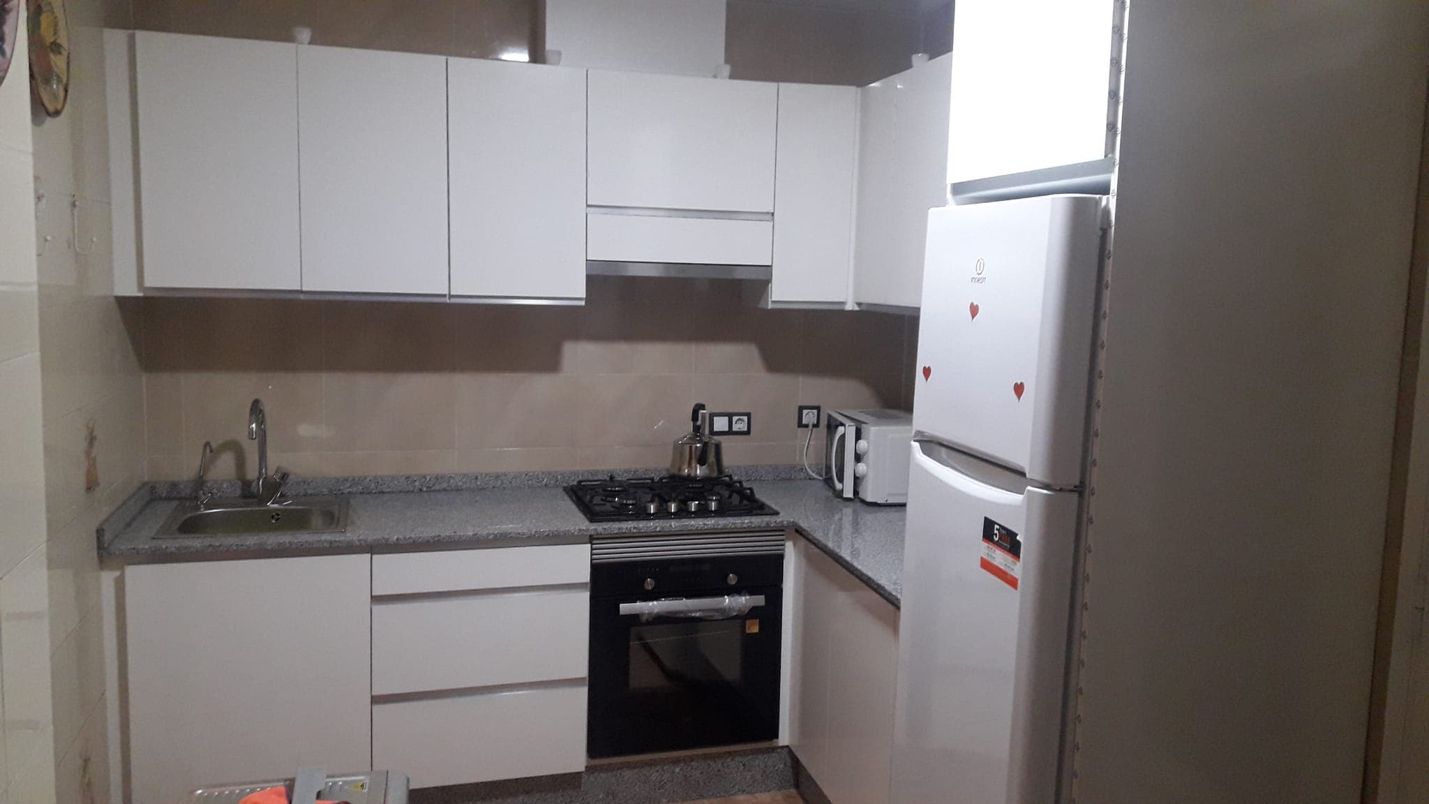 Cocina reformada con muebles blancos y electrodomésticos nuevos