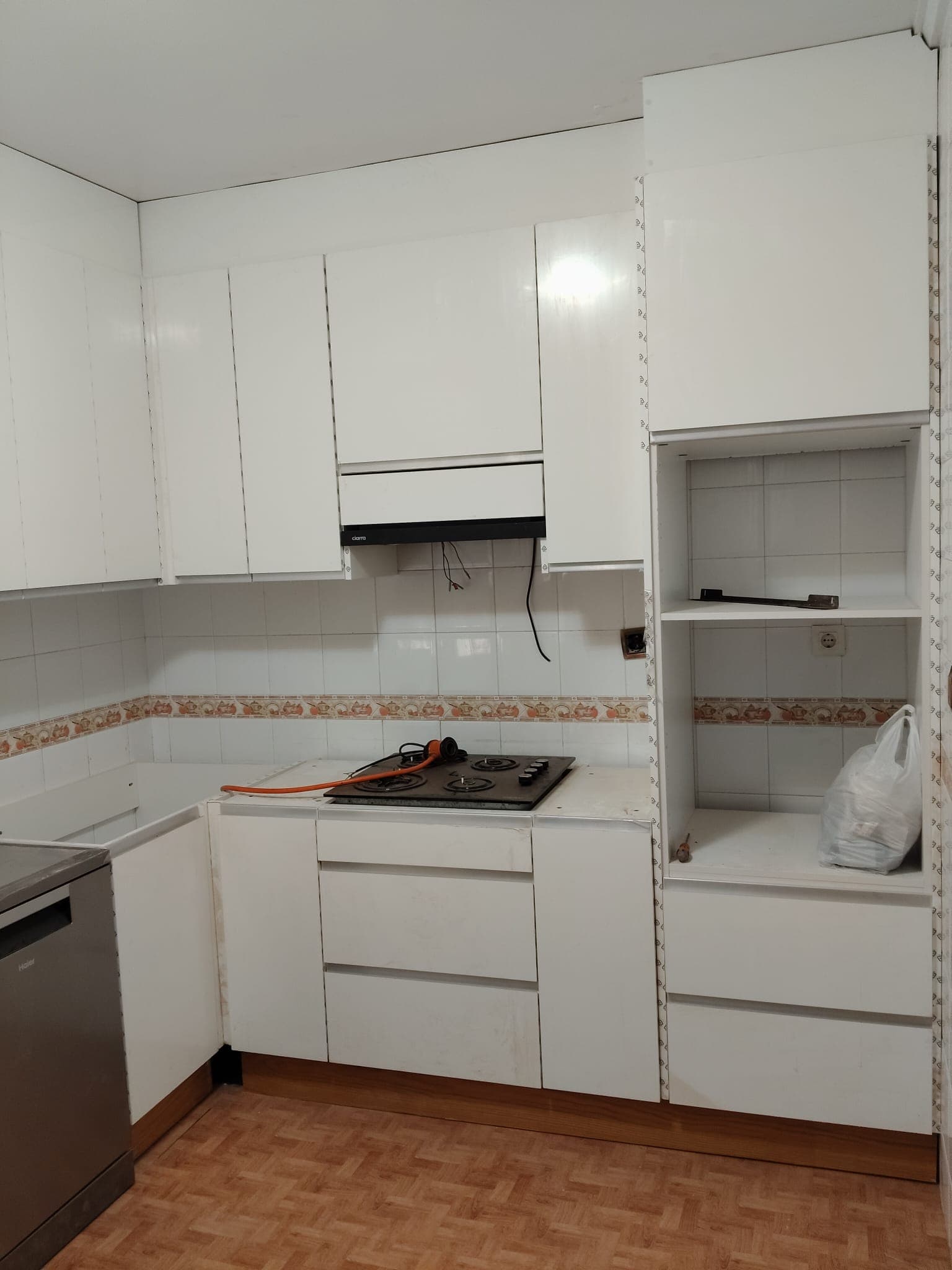 Cocina en obra con placa de gas y muebles blancos instalados