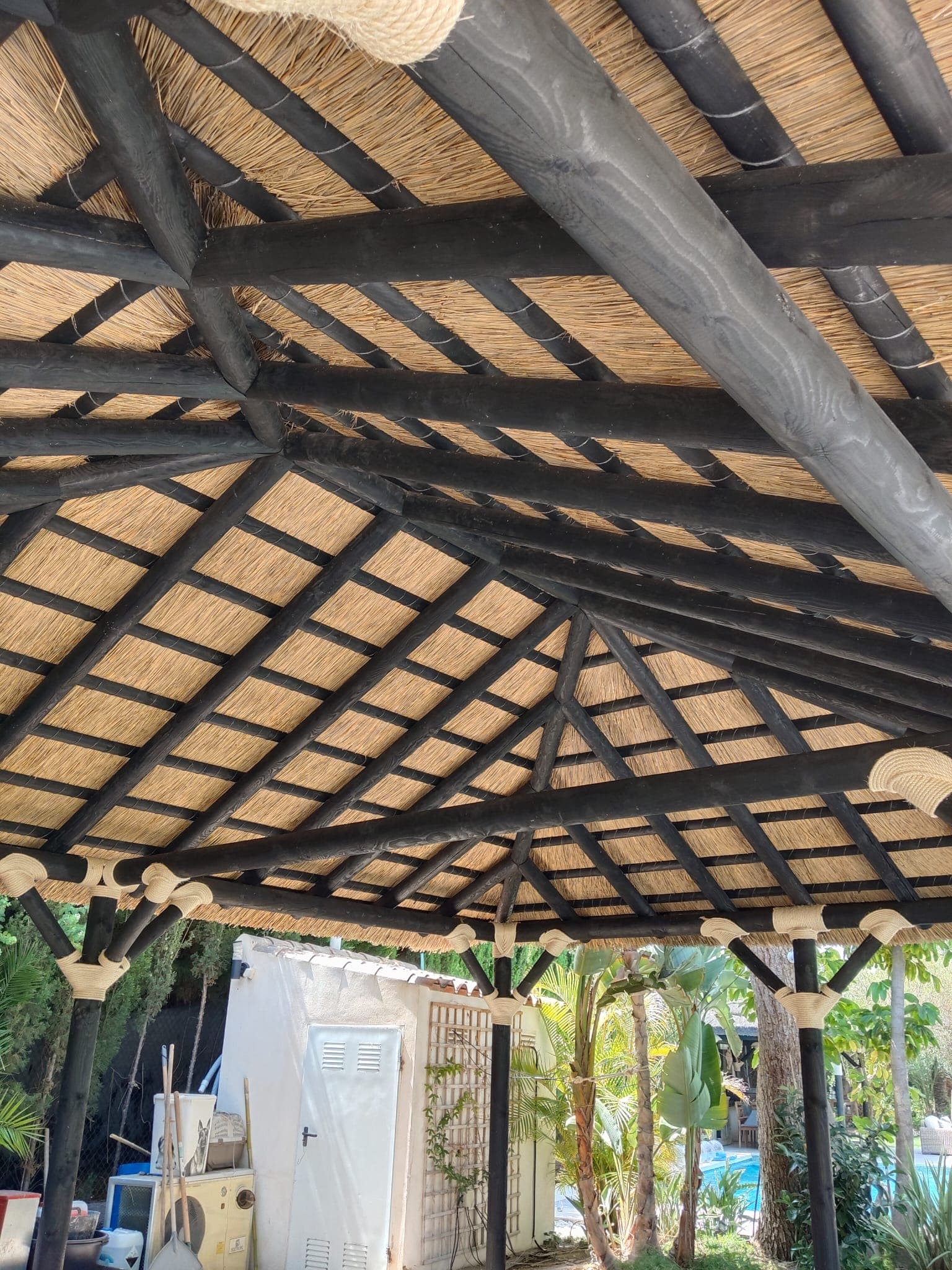 Pérgola de madera con techo de cañizo junto a una piscina