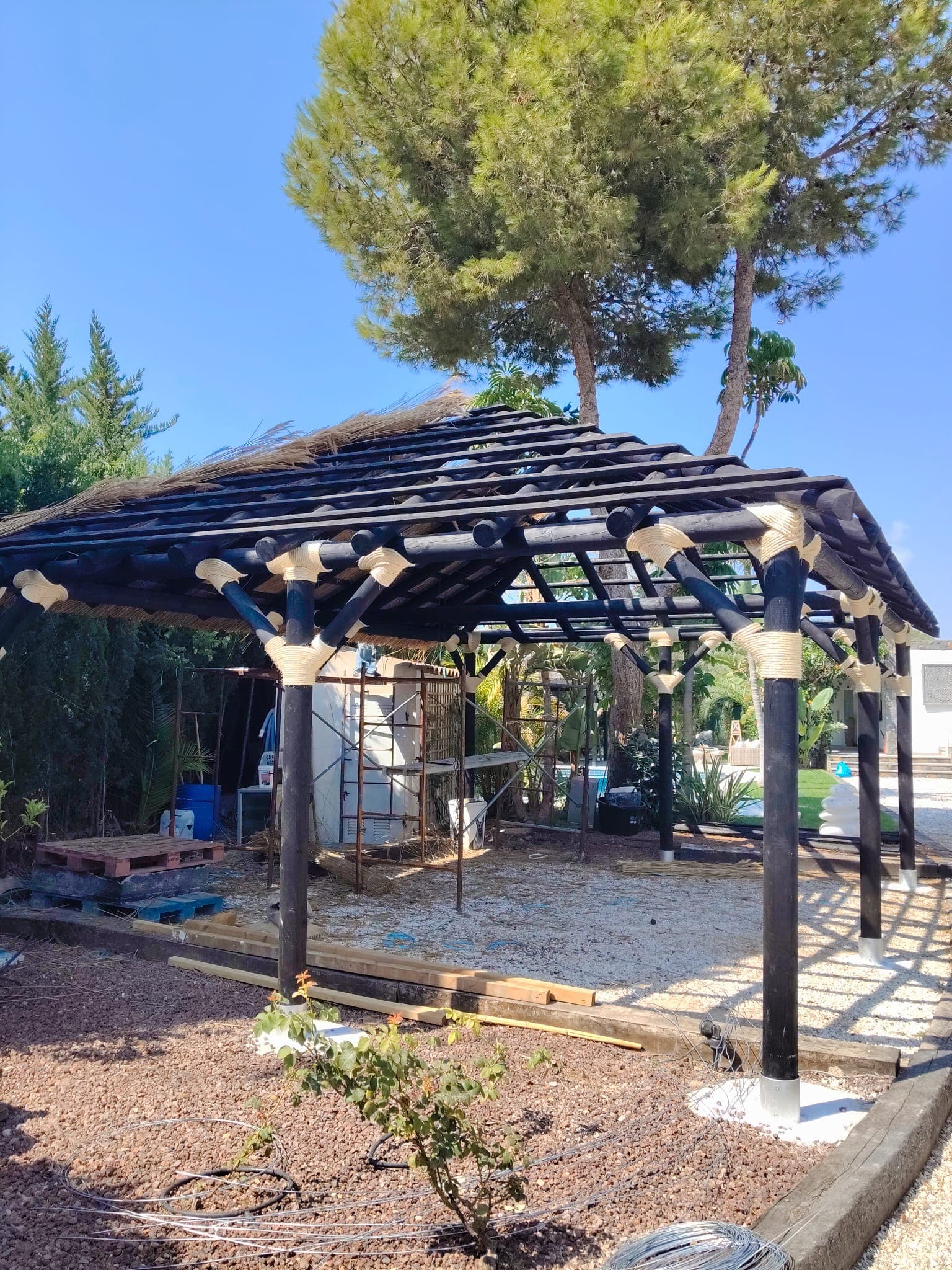 Pérgola de madera en construcción con techo de cañizo